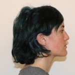Profile view: person with short dark hair, neutral expression, light top