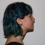 Profile view: person with blue hair, dark top, facing right